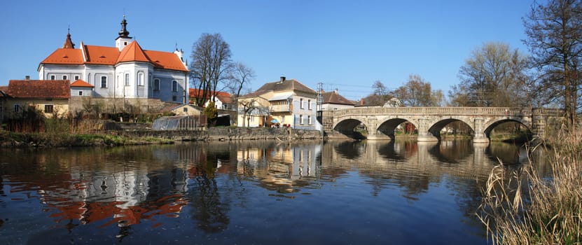 Small town of Mirovice in the Southern Czech Republic at dusk time. Old Bridge over the river Skalice and local church are well visible on this panorama