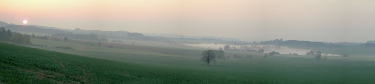           Sun is rising over the country in the spring. The lanscape is misty