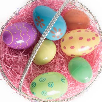 Decorated Easter eggs in Easter basket with pink decorative grass.  Isolated on white background.