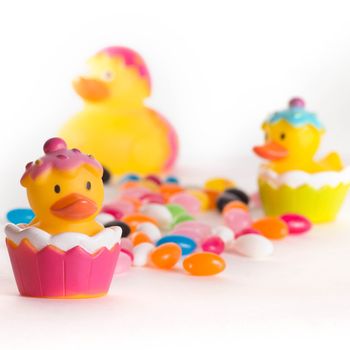 Easter rubber ducks with colorful jelly beans isolated on white background