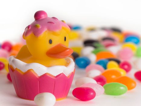 Easter rubber ducks with colorful jelly beans  out of focus in the background.  Isolated on white background