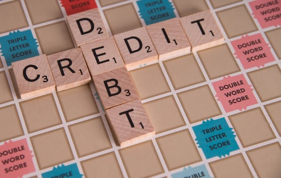 "Credit Debit" concept spelled out in Scrabble letters on Scrabble board