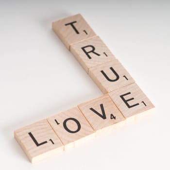 True Love Concept.  Wooden Scrabble letters spelling out phrase "True Love". Isolated on white background with light shadow