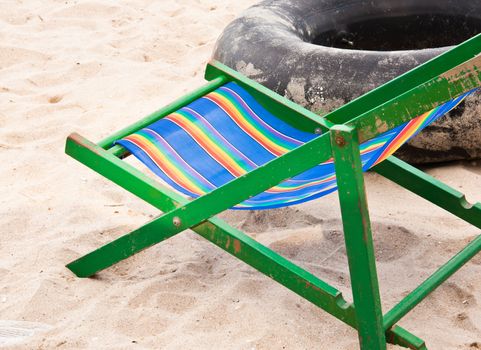 Folding chair and  tire wheel at the beach of the sea.