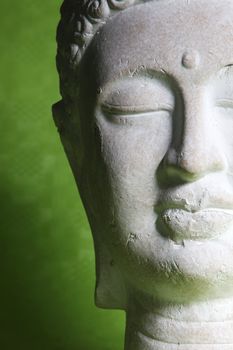 Closeup of the face of a beautiful tranquil stone statue of Buddha meditating for inner peace, tranquillity and enlightenment