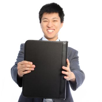 Smiling handsome young Asian businessman holding out a large black leather binder towards the camera isolated on white