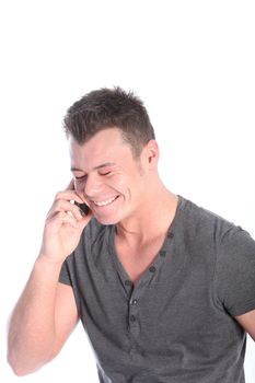 Handsome young man laughing happily while listening to a conversation on his mobile phone isolated on white