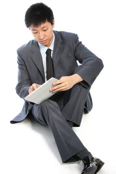 Young businessman sitting on white background and working on his tablet