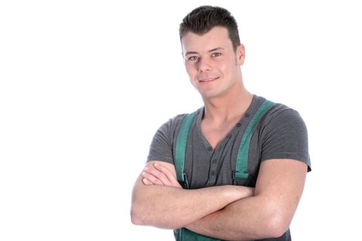 Handsome fit strong young man in dungarees standing with his arms folded looking at the camera with a smile islated on white