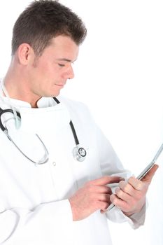 Handsome young male doctor in a labcoat and mask standing consulting information on a tablet isolated on white