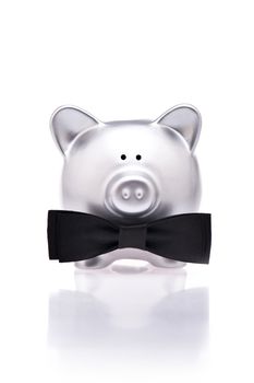 Silver piggy bank with bow tie over white