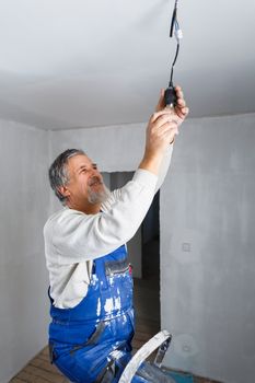 Senior man installing a bulb in a freshly renovated appartment