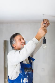 Senior man installing a bulb in a freshly renovated appartment