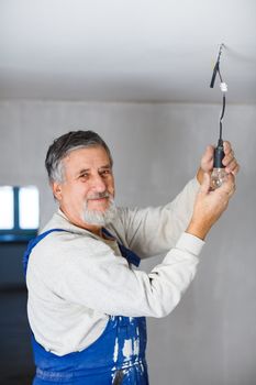 Senior man installing a bulb in a freshly renovated appartment