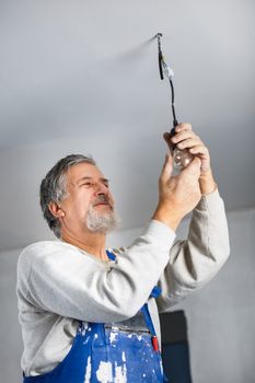 Senior man installing a bulb in a freshly renovated appartment