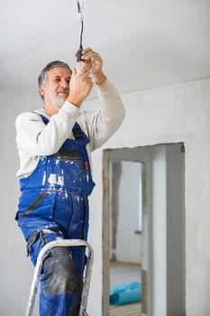 Senior man installing a bulb in a freshly renovated appartment