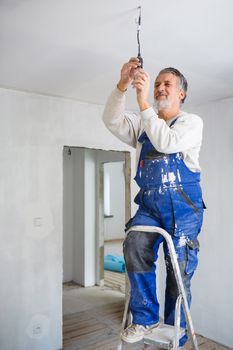 Senior man installing a bulb in a freshly renovated appartment