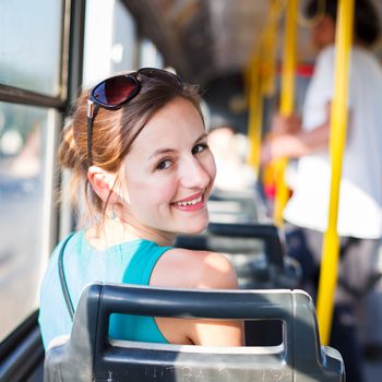 Pretty, young woman on a streetcar/tramway, during her commute to work/school (color toned image; shallow DOF)