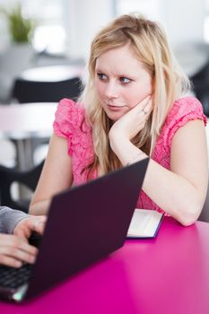 Two college students having fun studying together, using a laptop computer on campus, between classes (shallow DOF, color toned image)