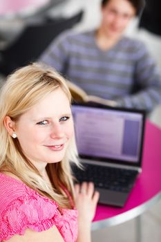 Two college students having fun studying together, using a laptop computer on campus, between classes (shallow DOF, color toned image)