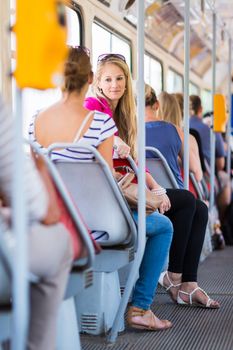 Pretty, young woman on a streetcar/tramway, during her commute to work/school (color toned image; shallow DOF)