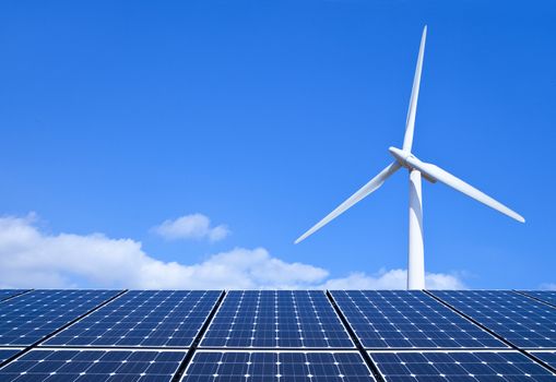 Solar panels and wind turbine against blue sky

