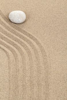 zen stone in soft sand with lines
