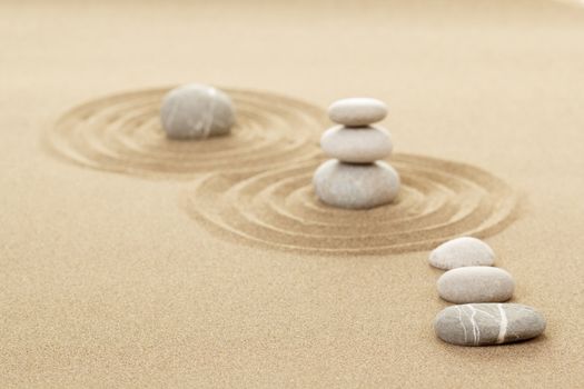 Balance of three zen stones in sand with shallow focus