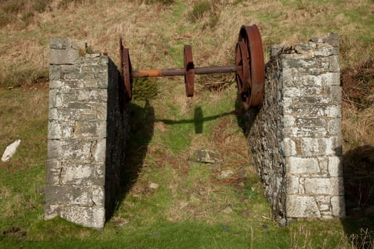 Two support walls hold up vintage, industrial rusty wheel turning gear.