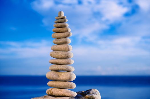 Balancing of white long pebbles on the sea coast