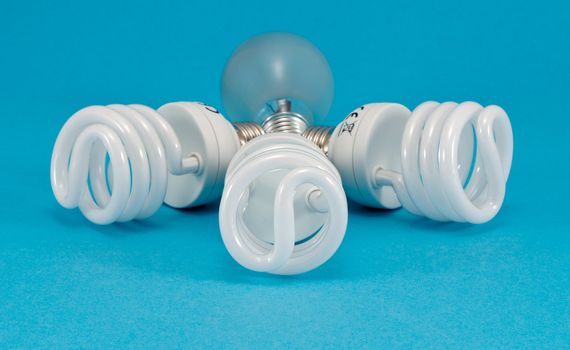 novel new modern fluorescent lights and old incandescent heat bulb on blue background. economic technology for less electricity energy consumption.