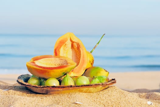 Exotic tropical fruit on the leaves plate on the sandy beach