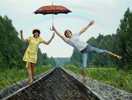 Young couple under rain on railroad track
