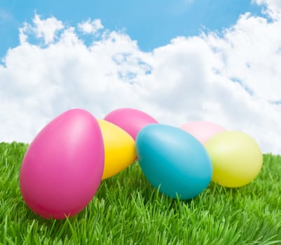Color Easter Eggs in Grass under Sunny Blue Sky