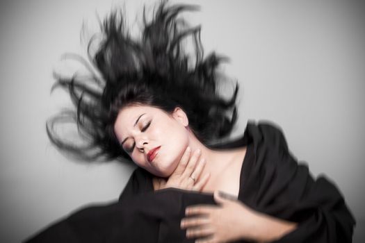 Brunette woman in studio shot with wind on hair .