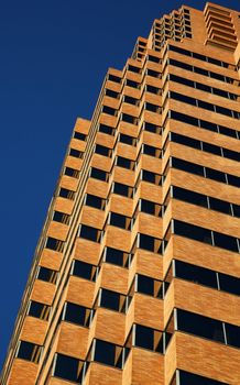 Close up vertical view of modern tan office building on a clear day