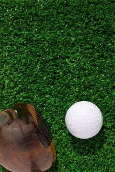 Golf ball and driver on green grass