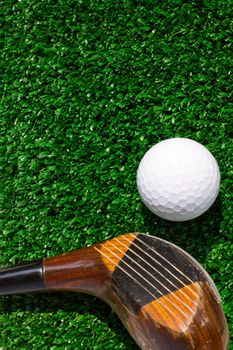 Golf ball and putter on green grass