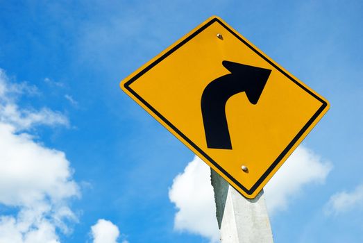 Road sign warning of dangerous left curve on blue sky