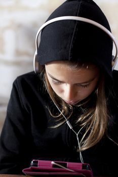 A teenager looking down on a tablet, listening to music. 