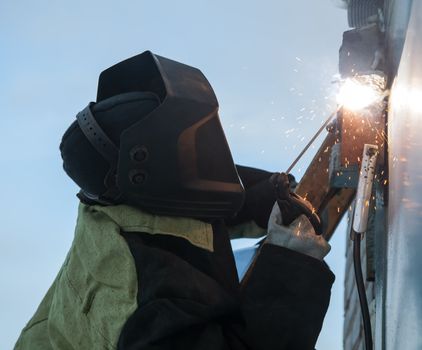 Welder at work on the background of blue sky