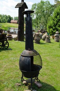 retro rusty barbeque smokehouse steel tool with chimney and stone vintage decorations in rural garden park.