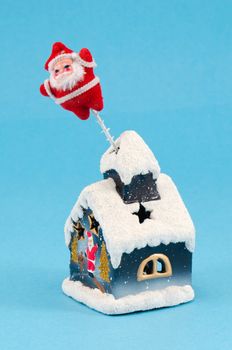 christmas house decoration with santa in chimney on blue background.