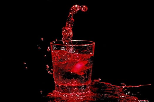 Ice cube splashing into a glass of red wine