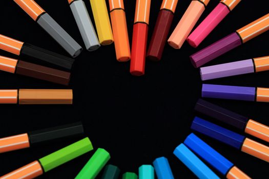 Color Pens in form of love on black background