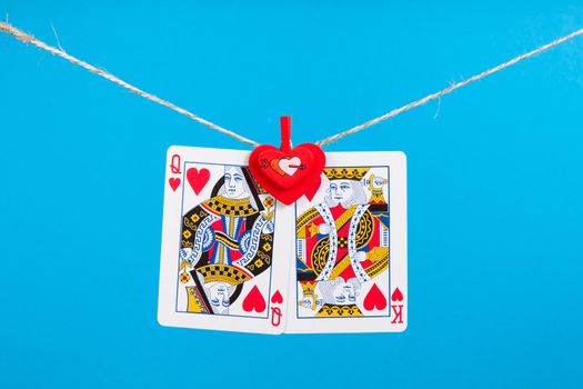 King and Queen of Hearts isolated with clothes peg rope over blue background