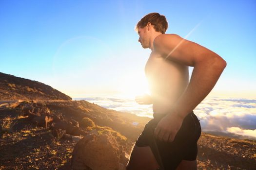 Runner athlete running. Sport man jogging outdoor in sunshine at sunset in scenic nature. Fit muscular male fitness athlete training trail running for marathon run. Sporty fit athletic man working out in topless outside.