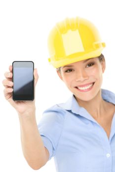 Engineer or architect woman showing smart mobile phone copy space. Young female professional smiling friendly and happy wearing yellow hard hat isolated on white background. Multicultural woman.