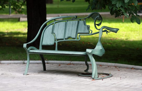 Metal abstract form forged bench in summer park 