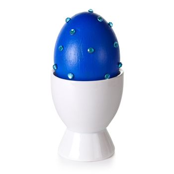 Easter egg on stand on white background. Blue eggshell hand decorated